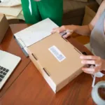 Dua orang mengemas pesanan online di meja kerja bisnis kecil